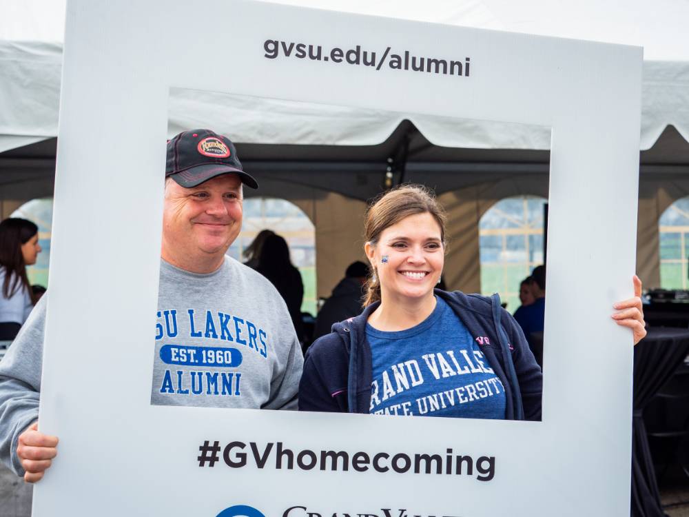 2 Alumni pose with the #GVhomecoming sign